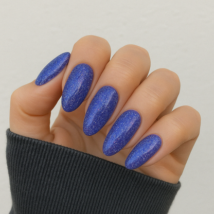 Starborn – Djupviolett med glitter och skimrande blå och rosa inslag / glittrigt gellack / gel polish på modellhand – Salongskvalitet UV/LED-nagellack – Mandel-formade naglar